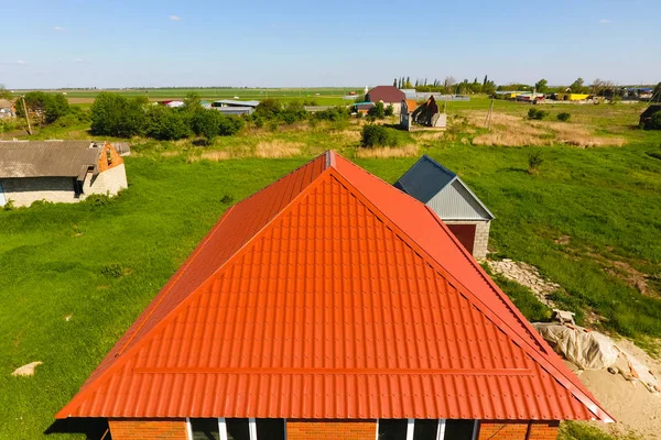 Haus mit orangefarbenem Dach aus Metall, Draufsicht. metallisches Profil lackiert Wellpappe auf dem Dach. — Stockfoto