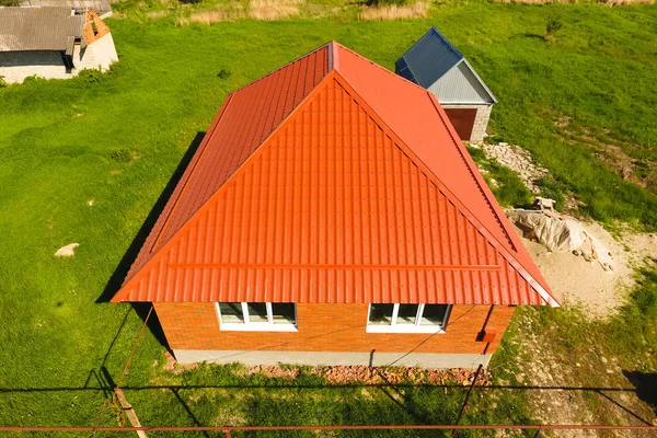 Woning met een oranje dak gemaakt van metaal, top uitzicht. Metalen profiel geschilderd gegolfd op het dak. — Stockfoto