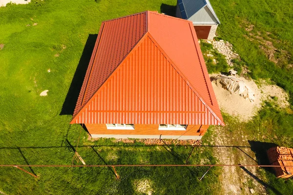 Casa con un techo naranja de metal, vista superior. Perfil metálico pintado ondulado en el techo . — Foto de Stock