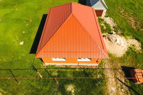 Hus med en orange tak gjorda av metall, top view. Metalliska profil målad wellpapp på taket. — Stockfoto