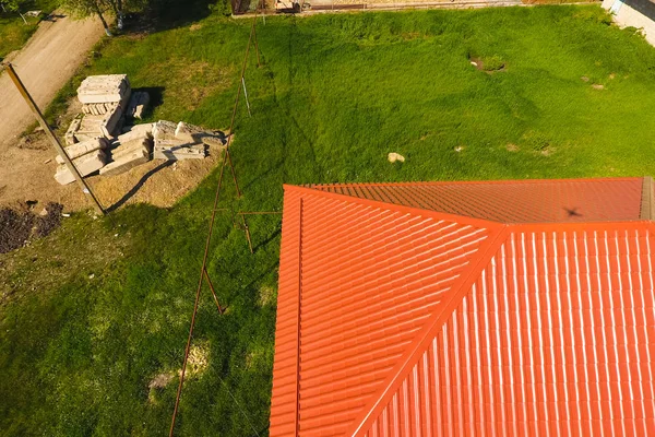 Casa com um telhado laranja feito de metal, vista superior. Perfil metálico pintado ondulado no telhado . — Fotografia de Stock