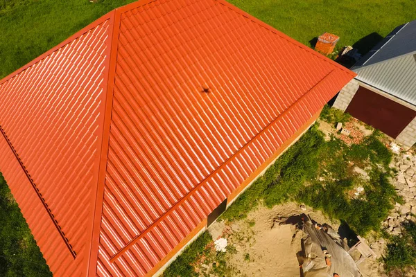 Maison avec un toit orange en métal, vue sur le dessus. Profilé métallique peint ondulé sur le toit . — Photo