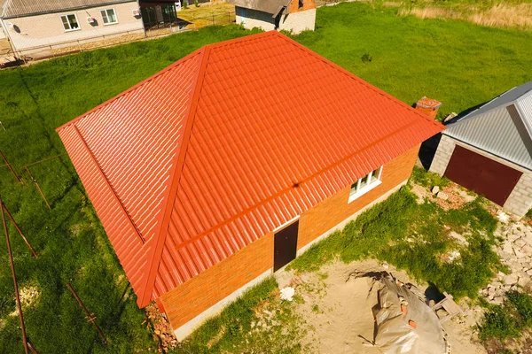 Hus med en orange tak gjorda av metall, top view. Metalliska profil målad wellpapp på taket. — Stockfoto
