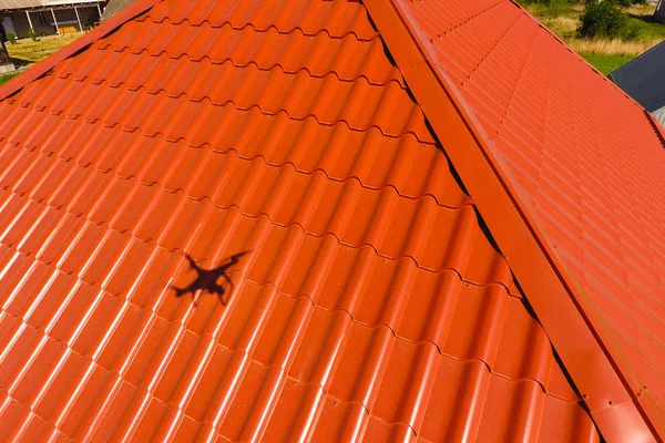 House with an orange roof made of metal, top view. Metallic profile painted corrugated on the roof. — Stock Photo, Image