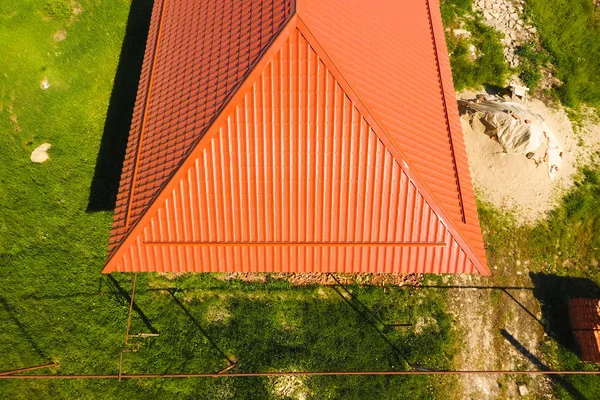 Haus mit orangefarbenem Dach aus Metall, Draufsicht. metallisches Profil lackiert Wellpappe auf dem Dach. — Stockfoto