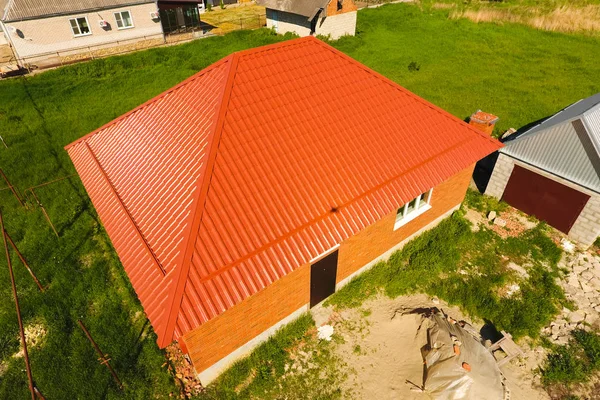 Casa con un techo naranja de metal, vista superior. Perfil metálico pintado ondulado en el techo . — Foto de Stock