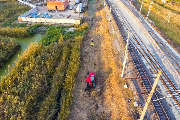 Die Planierraupe räumt den Platz entlang der Bahngleise frei. Harken von Schilf durch Planierraupe — Stockfoto