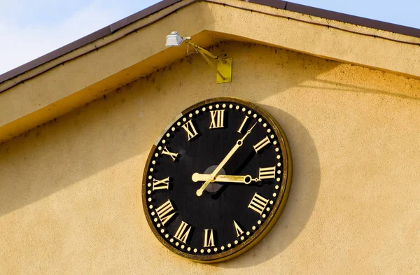 Reloj con números romanos en la parte delantera de la casa Mira la cara — Foto de Stock