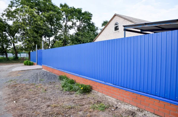 Fence and gate from sheets of blue corrugated metal.