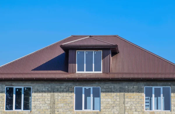 House of cinder block. House with plastic windows and roof of corrugated sheet. Roofing of metal profile wavy shape on the house with plastic windows