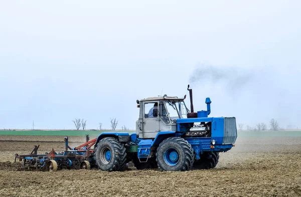 Bujna i spulchniają glebę, na pola przed siewem. Traktor orze pole z pług — Zdjęcie stockowe