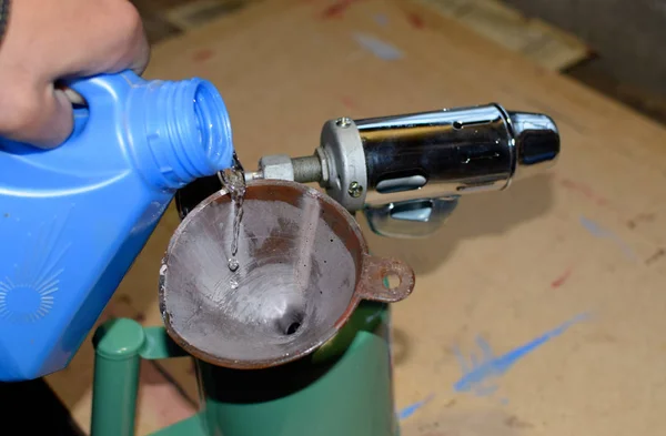 Pouring gasoline blowtorch through the funnel — Stock Photo, Image