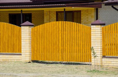 Oluklu metal profil çatısı ve ahşap çit tuğla ev. Güzel manzara cephe. Stil tasarım