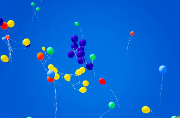 Sokszínű golyók, héliummal töltve, repülnek a kék égen — Stock Fotó