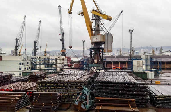 The metal rods folded on the port site for export. Temporary storage in the port of raw materials. Port cargo and cranes. — Stock Photo, Image