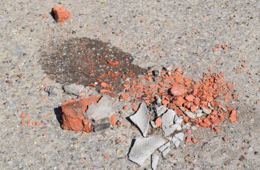 Asfalt üzerinde kırık tuğla ve kayrak parçaları