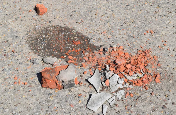 Asfalt üzerinde kırık tuğla ve kayrak parçaları