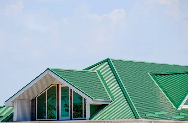 有塑料窗和波纹板的绿色屋顶的房子。绿色屋顶的波纹金属型材、 塑料窗. — 图库照片