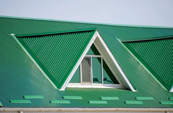Das Haus mit Kunststofffenstern und einem begrünten Dach aus Wellblech. Grünes Dach aus Wellblechprofilen und Kunststofffenstern. — Stockfoto