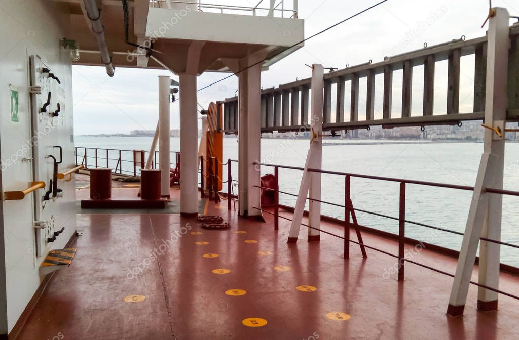 The deck of a cargo ship. Red floor and white walls.