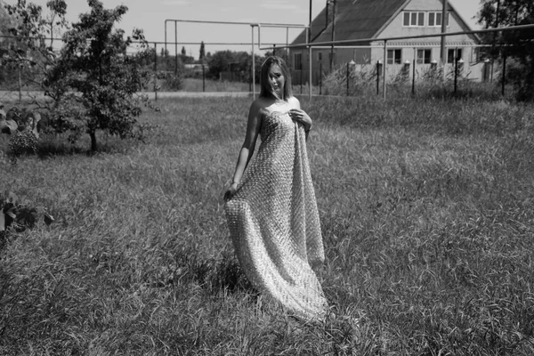 Zwart-wit foto, meisje in de tuin op een weide in een jurk. — Stockfoto