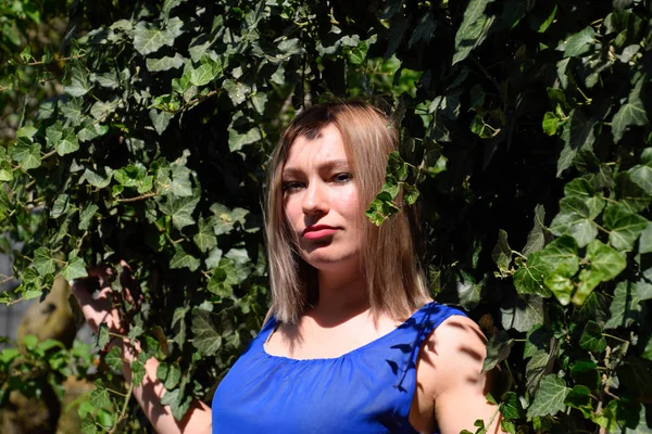 Portrait d'une fille en robe bleue sur fond de tonnelle verte de lierre . — Photo