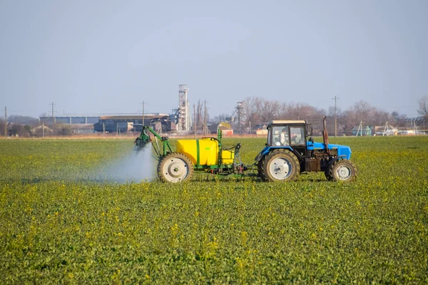Tracteur fertilise un champ de canola, pulvérisation d'engrais avec un tracteur . — Photo