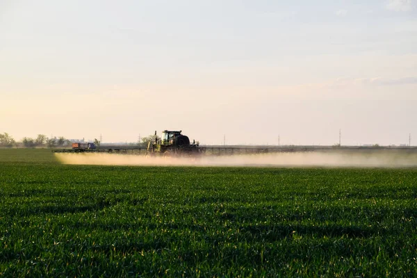 Traktor versprüht mit Hilfe einer Spritze Flüssigdünger auf jungen Weizen im Feld. — Stockfoto