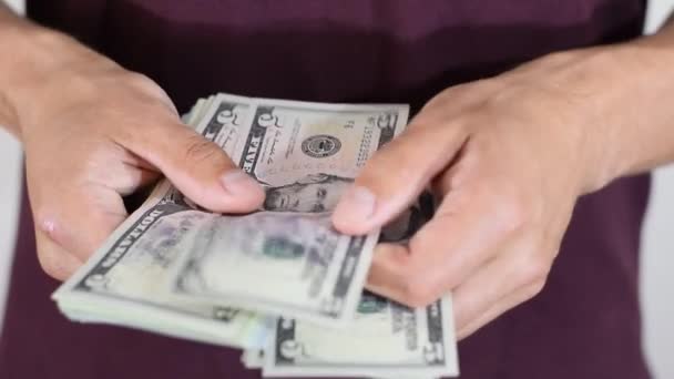 Человек случайно пересчитывает пачку долларов в руках. Деньги в долларах — стоковое видео