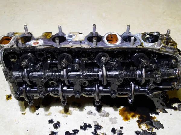 The head of the block of cylinders. The head of the block of cylinders removed from the engine for repair. Parts in engine oil. Car engine repair in the service