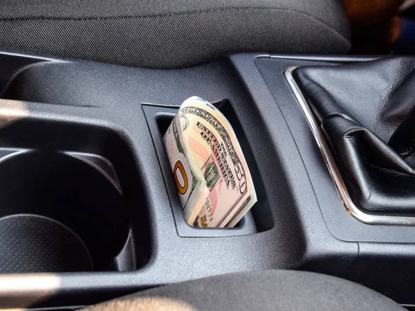 In der Nische der Mittelkonsole des Autos liegen mehrere Dollarnoten. das Geld im Auto lizenzfreie Stockbilder