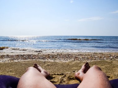 Bir adam bir plaj arka planda bacaklar. Bir adam sahilde bir amatrace yatıyor ve istirahat ediyor. Hemen bacaklarını açıp çerçeve.