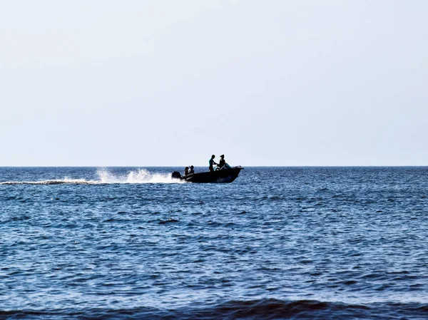 El barco se precipita junto al mar. En la gente del barco. Paisaje marino por la noche. Silueta de una lancha a motor y gente en ella contra el fondo de la distancia del mar —  Fotos de Stock