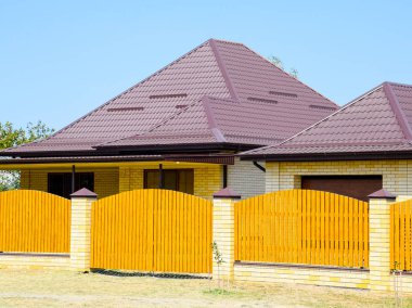 Oluklu metal profil çatısı ve ahşap çit tuğla ev. Güzel manzara cephe. Stil tasarım