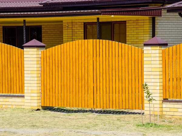 Casa de ladrillo con techo de perfil de metal corrugado y valla de madera. Hermosa vista de la fachada. Estilo de diseño — Foto de Stock