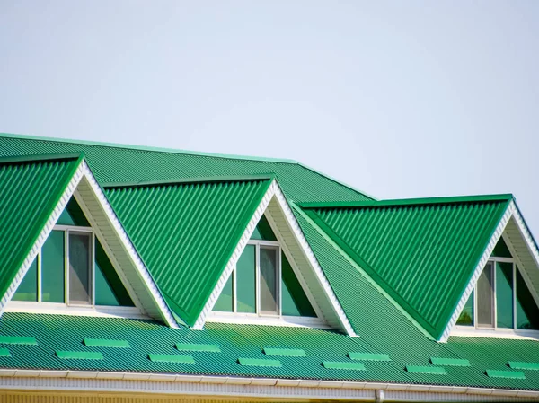 有塑料窗和波纹板的绿色屋顶的房子。绿色屋顶的波纹金属型材、 塑料窗. — 图库照片