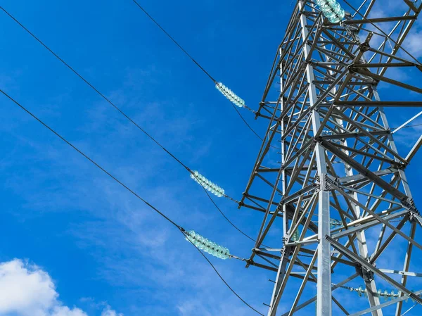 Supports high-voltage power lines against the blue sky with clouds. Electrical industry