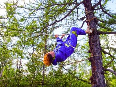 Bir turist kızın ağaçları arasında bir ip tırmanıyor