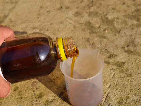 Наливание густого глифозатного раствора в стакан
