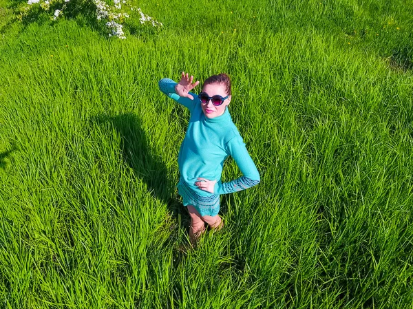 Молодая девушка в светло-зеленом платье на газоне с зеленой травой. Вид сверху на мужчину с высоты . — стоковое фото