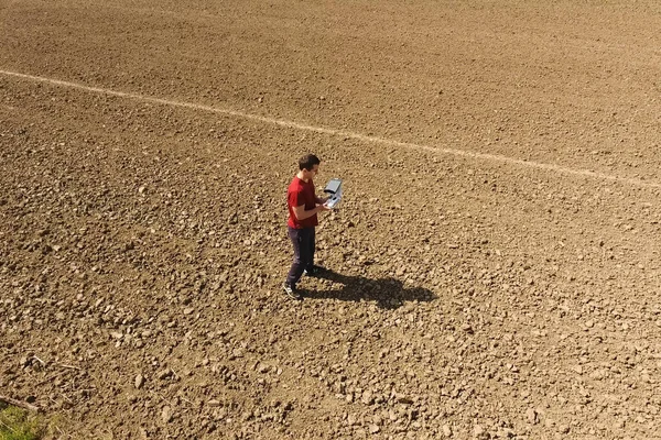 Un uomo con un telecomando dal drone. Un uomo sul campo controlla il drone . — Foto Stock