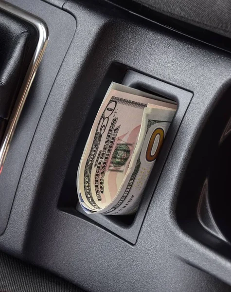 In der Nische der Mittelkonsole des Autos liegen mehrere Dollarnoten. das Geld im Auto — Stockfoto