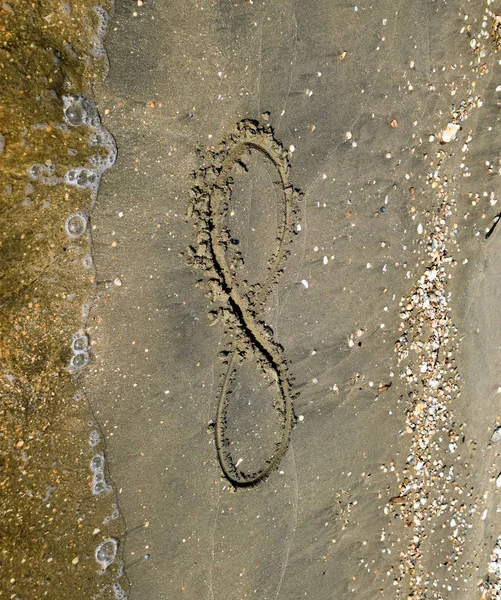 Знак бесконечности на море. Береговой песок на пляже. Символ бесконечности — стоковое фото