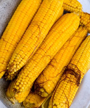 Alüminyum tepside haşlanmış mısır. Yakınlarda mısır var. Mısıra yakın çekim. Sarı haşlanmış taze mısır, yararlı ve lezzetli yiyecekler..