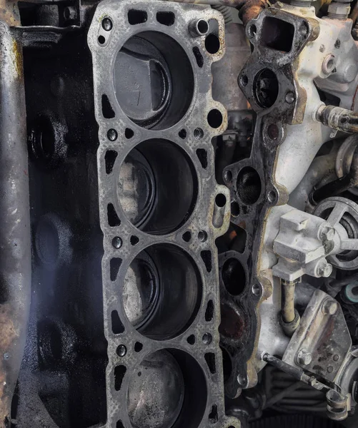 The cylinder block of the four-cylinder engine. Disassembled motor vehicle for repair. Parts in engine oil. Car engine repair in the service