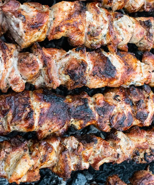 Faire frire du porc sur une brochette au-dessus d'un brasero. Retourner la viande sur les charbons. Chiche kebab appétissant . — Photo