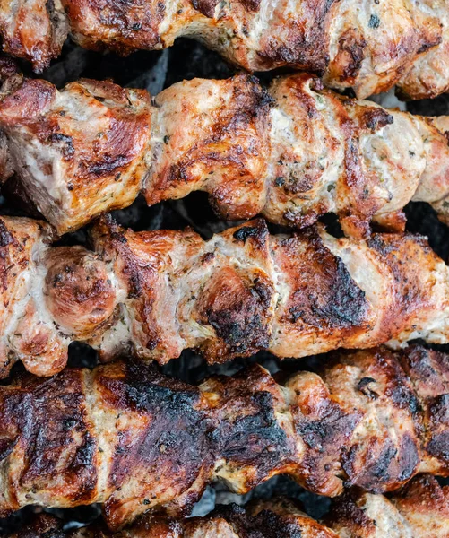 Frying pork on a skewer over a brazier. Turning meat over coals. Appetizing shish kebab. Royalty Free Stock Images