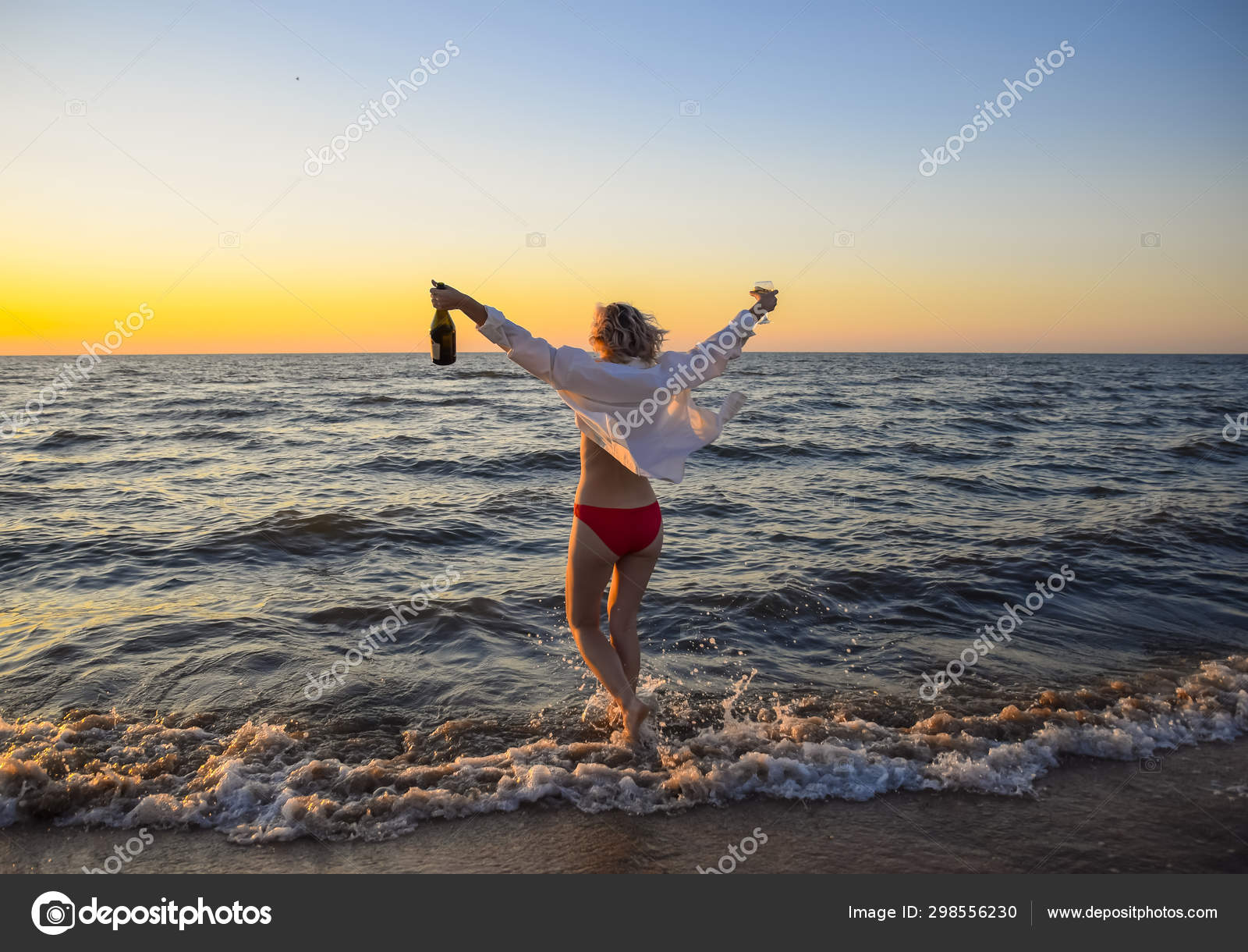 Jeune fille sur la plage de la mer avec une bouteille de champagne