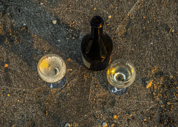Garrafa de champanhe e copos estão na areia da praia . — Fotografia de Stock