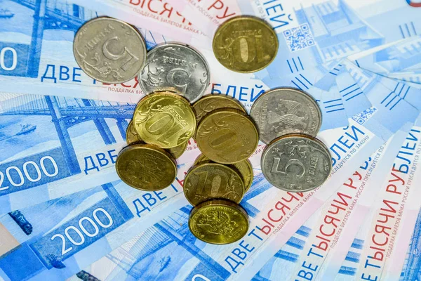 Russian banknotes and coins. A handful of coins on new Russian banknotes in denominations of 2000 and 200 rubles. — Stock Photo, Image